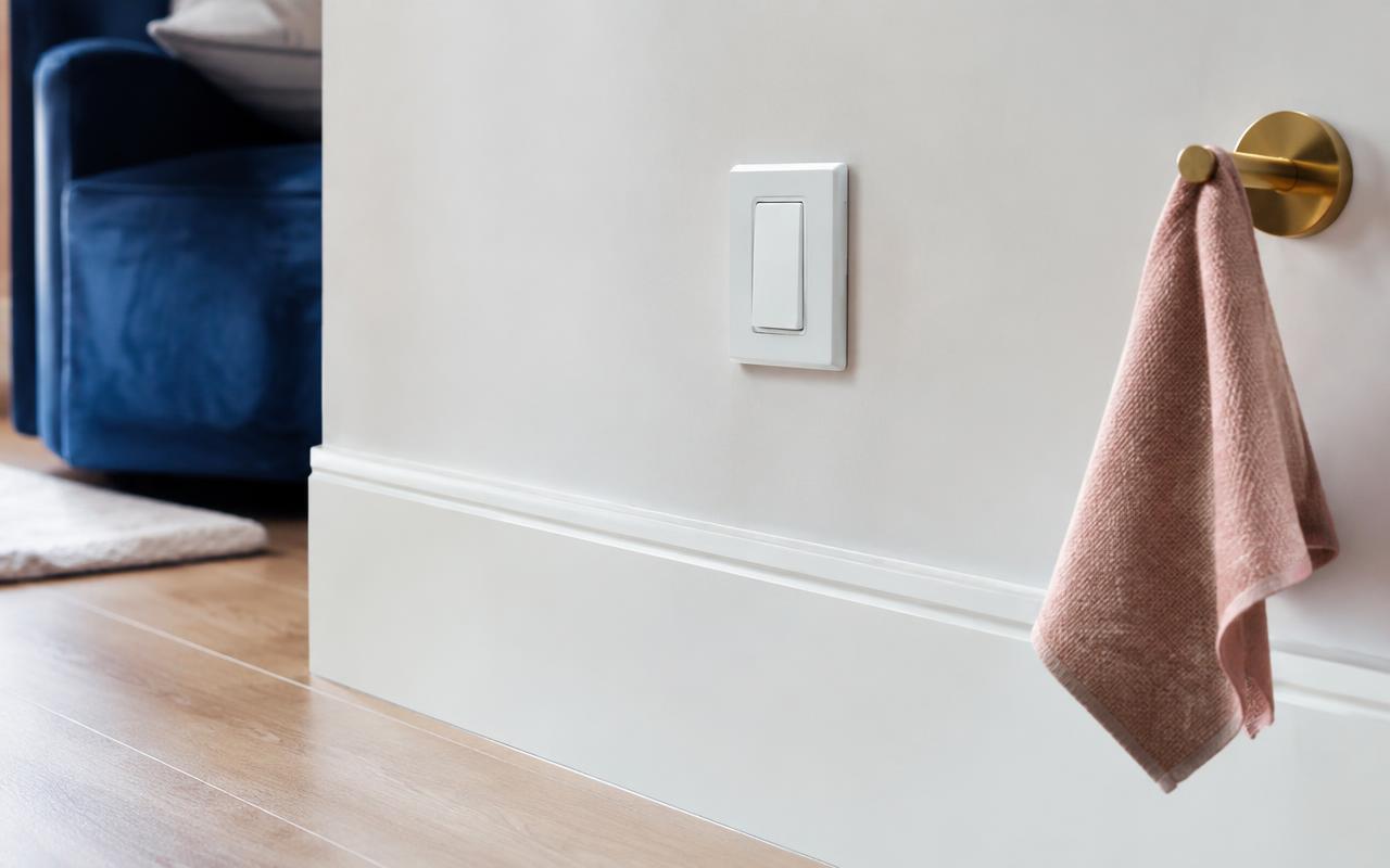 Clean white baseboard and light switch with a rose-colored cleaning cloth